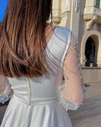 Rochie de mireasa albă lungă cu mâneci din perle, detaliu spate elegant, nasturi și tulle decorat.