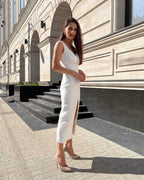 Rochie cocktail albă elegantă fără mâneci cu slit pe picior și croială ajustată.