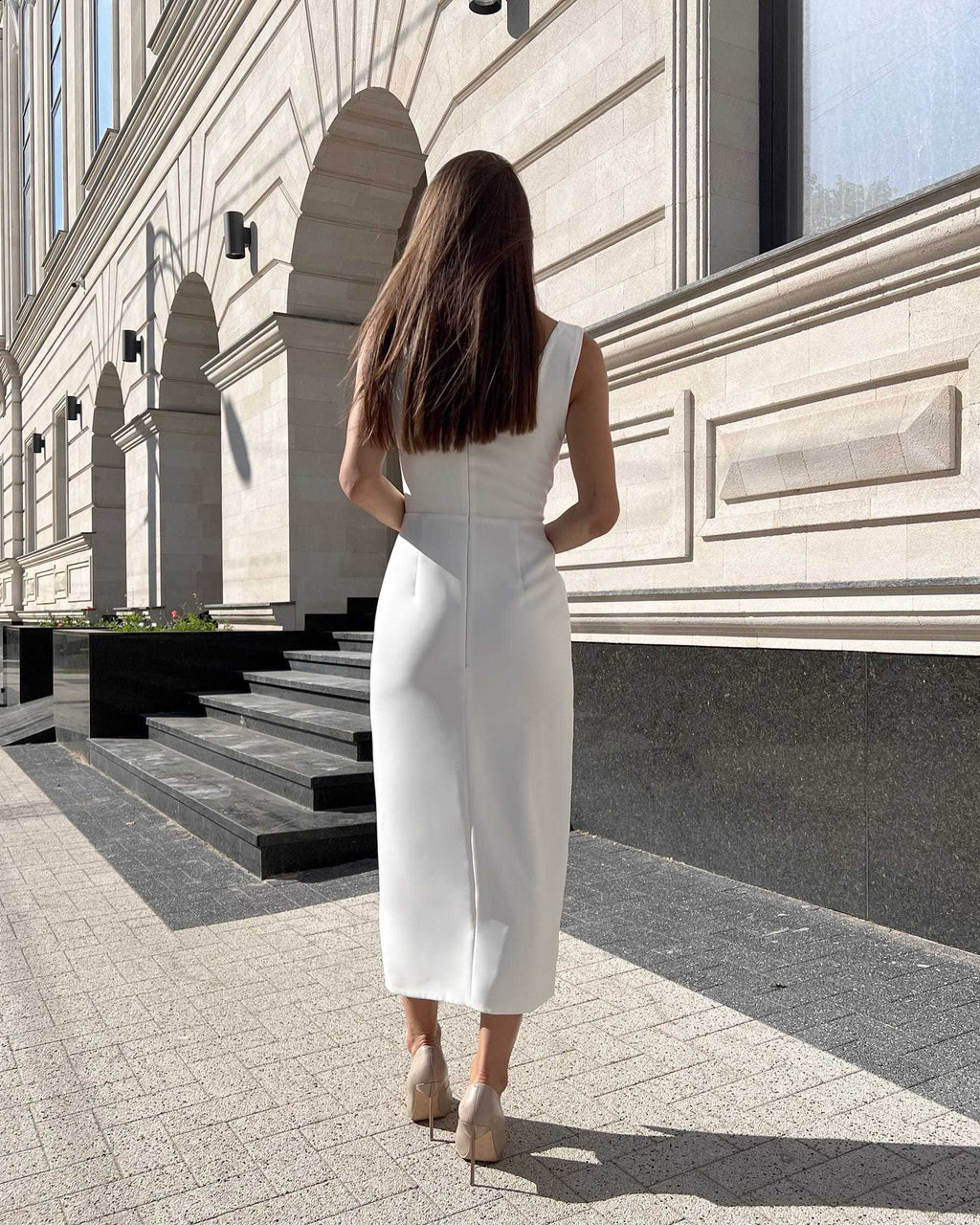 Rochie cocktail albă elegantă fără mâneci, ajustată, cu slit pe picior, vedere spate.