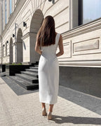 Rochie cocktail albă elegantă fără mâneci, ajustată, cu slit pe picior, vedere spate.