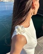 Rochie alba petrecere fără mâneci cu accesoriu floral și slit elegant, vedere laterală.