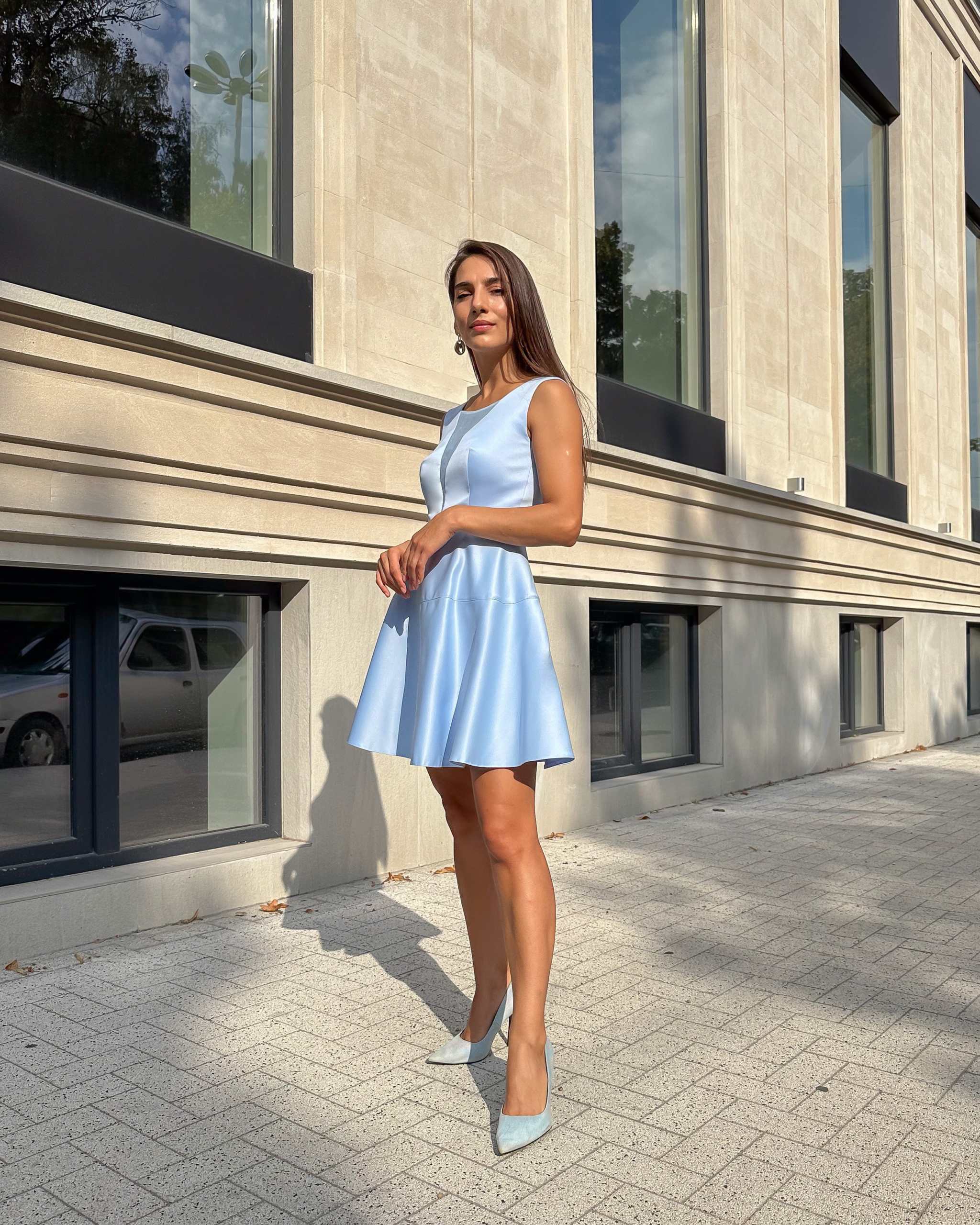 Rochie albastră scurtă cu decolteu semitransparent, purtată de model pe trotuar, elegantă și confortabilă pentru evenimente speciale.