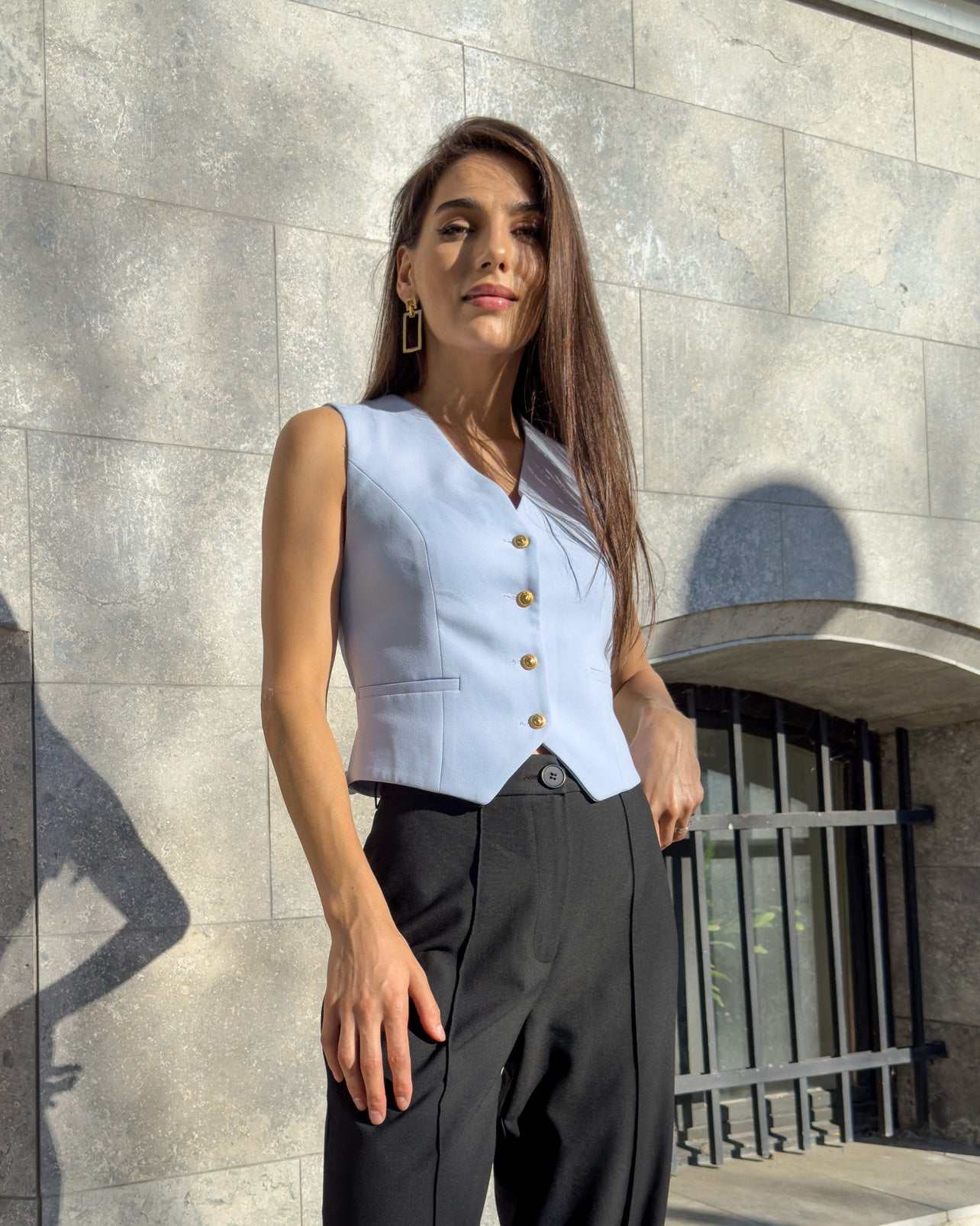 Vesta damă albastră cu croi cambrat și nasturi, material ușor elastic, decolteu în V.