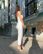 Rochie alba elegantă cu bretele și slit, lungime 108 cm, material crep elastic, potrivită pentru evenimente speciale.