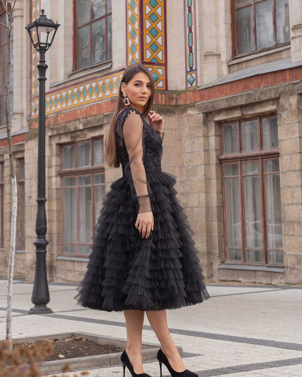 Rochie neagră de ocazie din dantelă cu mâneci lungi și fustă cu volane.